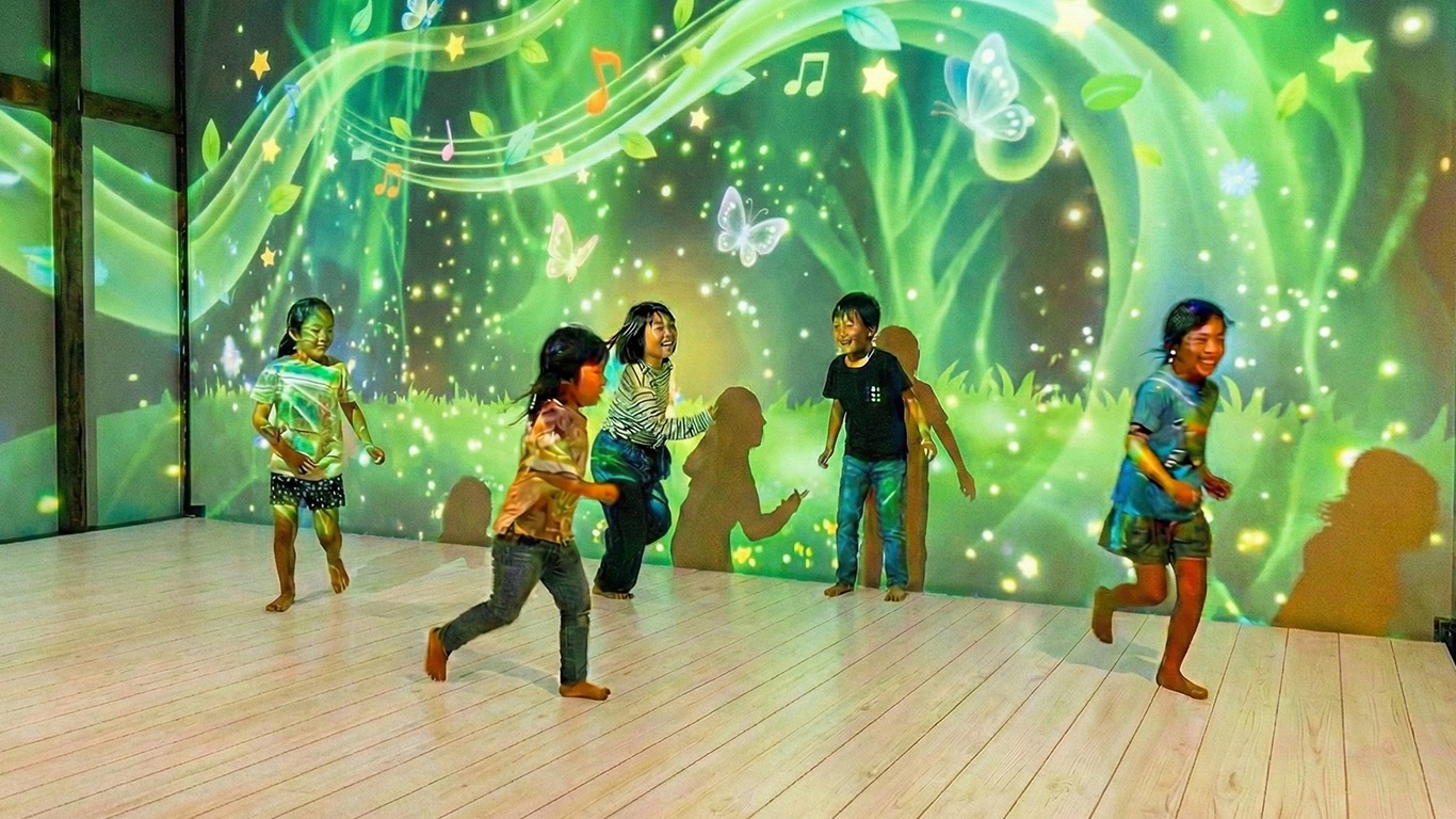 子どもたちがプロジェクションマッピングの下で楽しそうに走り回っている様子